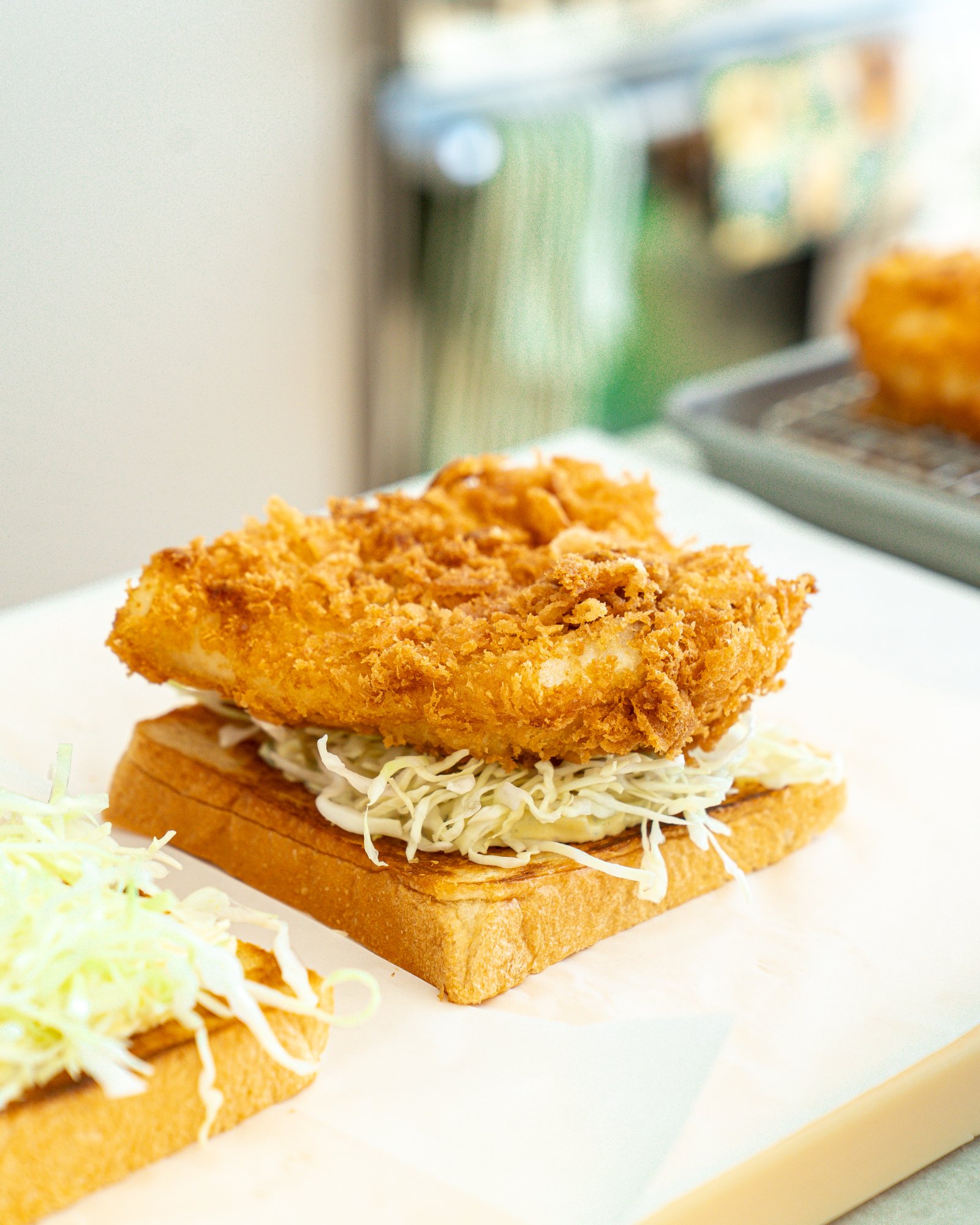 Fried cod katsu resting on cabbage and toasted shokupan