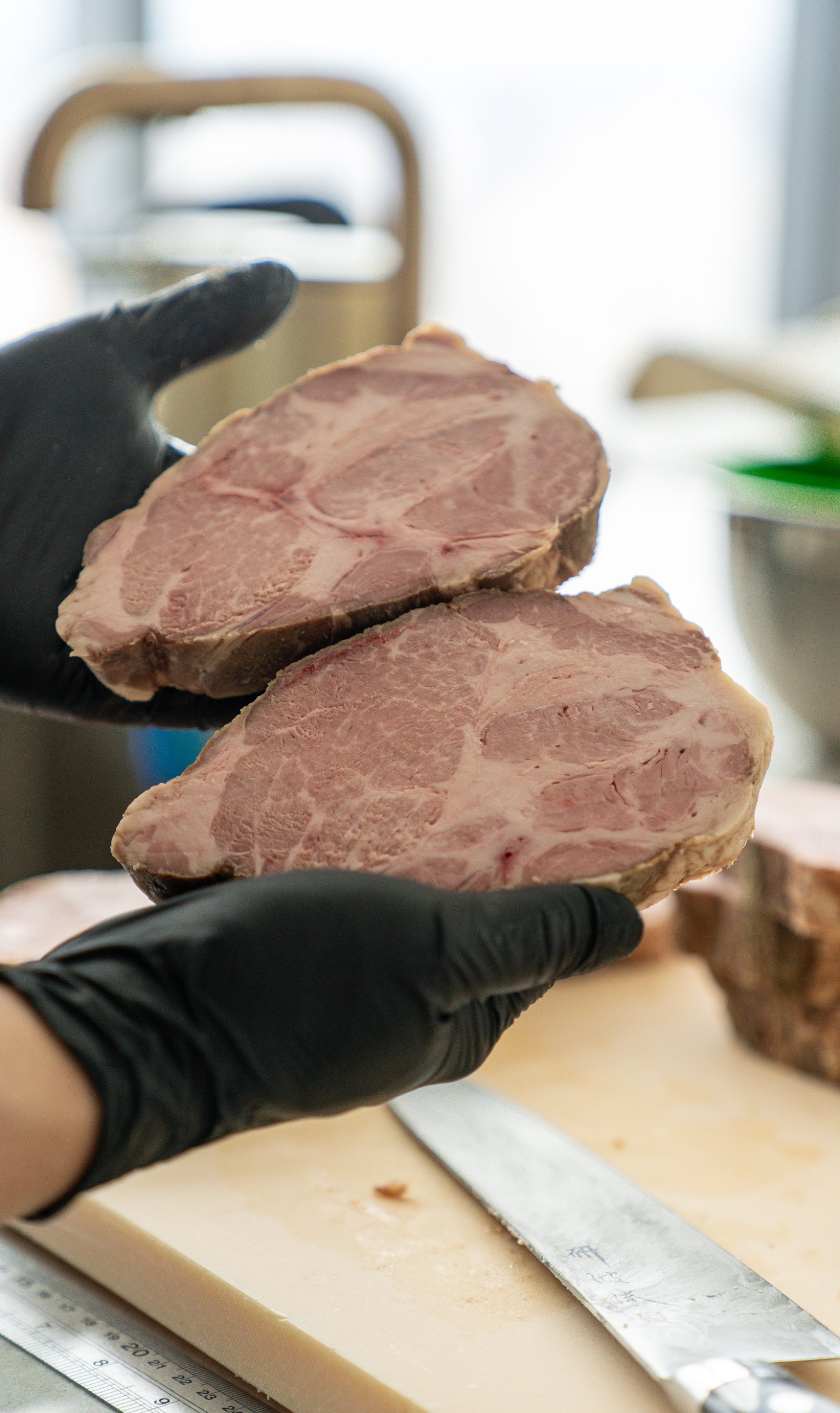 Two slices of cooked pork collar held up